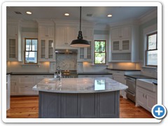 Check out the kitchen island, which features carrera marble and a food prep station with sink.  Also note the farmhouse sink at right.