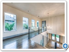 Chandelier and natural lighting show off the beauty and intricate detail of the signature fanned stairway and custom iron rails.
