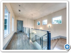 View of glass railing above allows visibility of iron railing below.  Catwalk runs between private, crown jewel master suite and rear three bedrooms, two baths and family room.