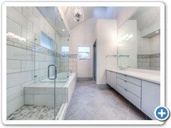 View of master bathroom, with spa and jetted tub, rain shower, and double vanity with carrera marble countertops.