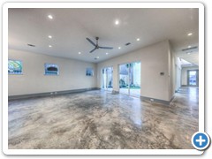 Expansive view of living room, courtyard and entry hall to front door with a glimpse of signature stairway on right